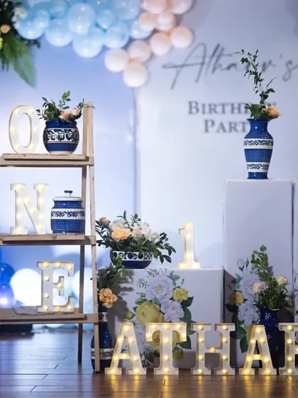 A detailed shot of the props used in the blue Moroccan theme, including the "ONE" marquee letters on a wooden shelf and the personalized "ATHARV" sign.