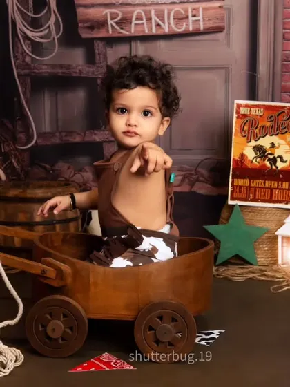 This little rancher is ready to take the reins, pointing right at the camera from his wooden wagon.