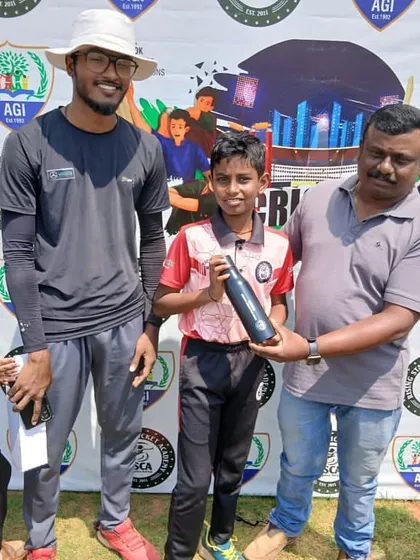 A player receives his award from an official, surrounded by his cheering teammates.