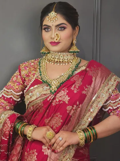 A confident pose from a Maharashtrian bride. The makeup is flawless, with a focus on creating a balanced look that complements her heavy jewelry and bright saree.