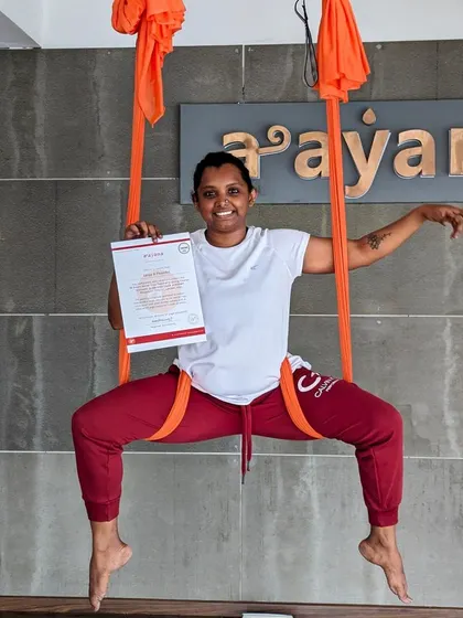A proud graduate of our aerial TTC, holding her certificate while striking a pose in the hammock.