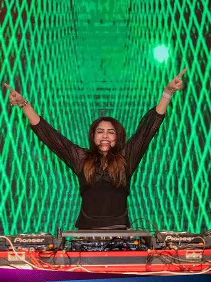 Arms raised in celebration in front of a massive green LED wall at Kaavaalaa 3.0. This shot captures the epic scale and success of the international music festival.