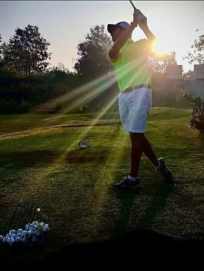 A golfer tees off as the sun sets, casting a golden glow over the course. This image captures the magic of playing during the golden hour at our Karjat location.