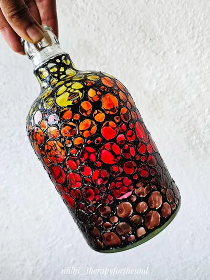 A glass bottle painted with a 'bubble' pattern in a fiery gradient of yellow, orange, and red. The stained-glass effect gives the bottle a warm, glowing appearance.
