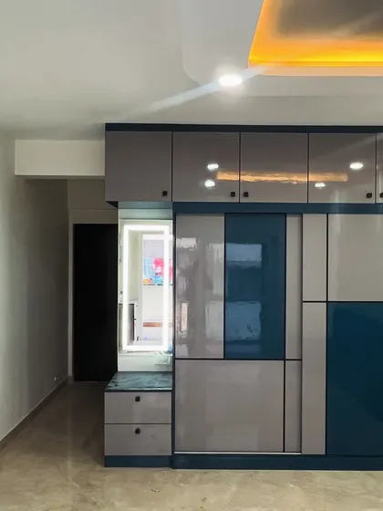 Color combinations and patterns play a vital role in design. This sliding wardrobe features a geometric pattern using grey and blue high-gloss laminates, paired with a built-in dresser with a backlit mirror.