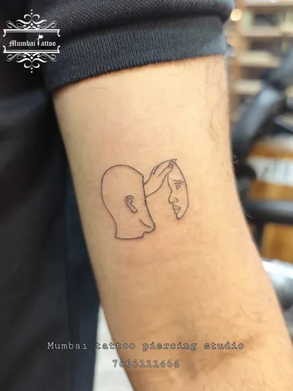 An abstract, thought-provoking tattoo of a head removing its own face like a mask. This fine line piece is a powerful conversation starter, showcasing our ability to translate complex ideas into minimalist art.
