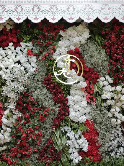 A lush floral wall in red, white, and green, featuring a golden monogram of the couple's initials. This serves as a personalized and luxurious photo opportunity for guests.