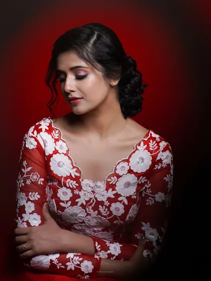 A Christmas-themed portrait for a makeup academy. The red and white outfit and the dramatic red background create a festive and glamorous look.