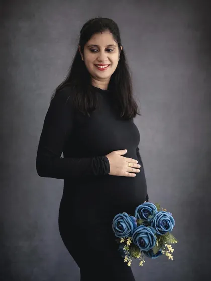 A sweet and simple solo portrait. The mom-to-be's gentle smile and the pop of color from the blue flowers create a lovely, calm image.