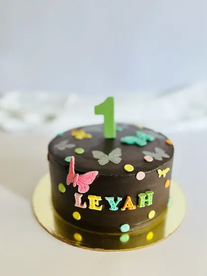 A simple and sweet chocolate cake for a little butterfly's first birthday. The colorful fondant butterflies and polka dots make it a cheerful and fun design for a first celebration.