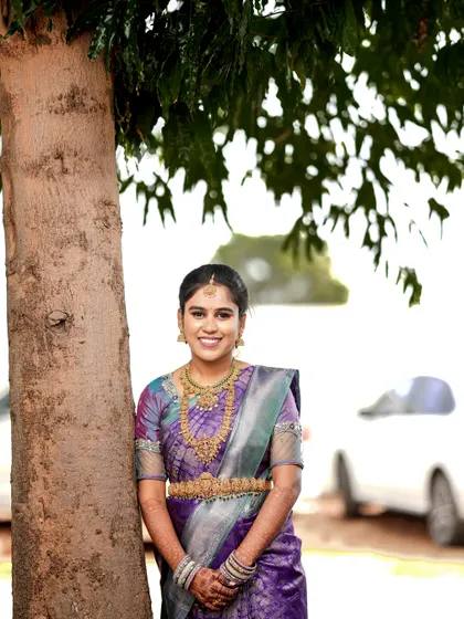 A beautiful outdoor portrait of the bride-to-be, with her purple saree standing out against the natural greenery.