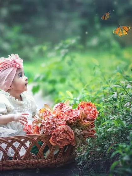 This wide shot shows the baby in her basket, surrounded by lush greenery and looking up at magical butterflies, creating a sense of wonder and enchantment.