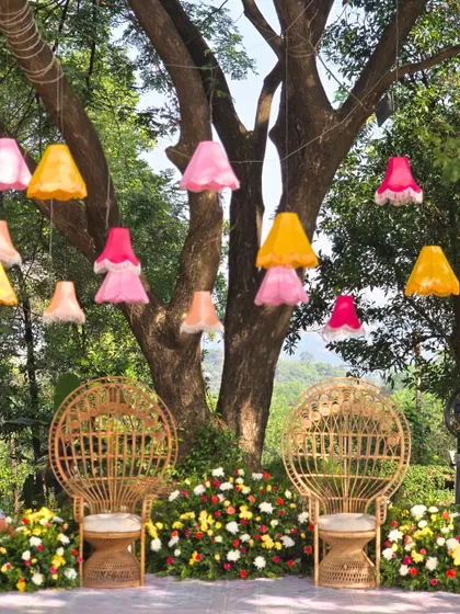 The seating area for the couple, framed by a large tree decorated with colorful lampshades. The design is whimsical, artistic, and perfect for a creative couple.