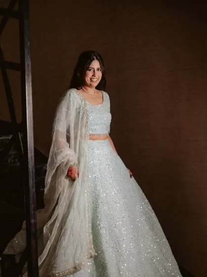 A full-length shot of the bride in her sparkling lehenga. The soft, elegant makeup perfectly balances the glamour of her outfit.
