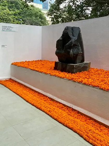 A sculpture by Stephen Cox is given a place of honor at the MAP preview, set against a bed of marigolds. This installation highlights the integration of cultural traditions and contemporary art within the museum's architectural framework.