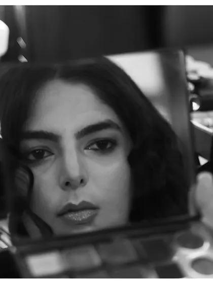 A reflective moment. This black and white photo shows the client's finished makeup in a compact mirror, highlighting the artistry and detail of our work.