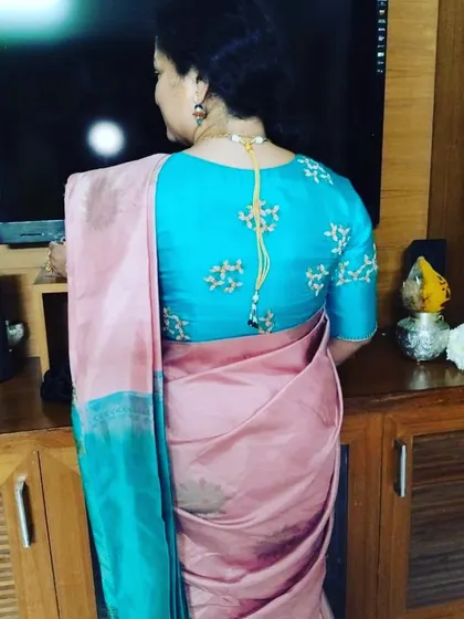A client wearing a sky blue blouse with simple, scattered embroidery. It pairs beautifully with her pink silk saree.