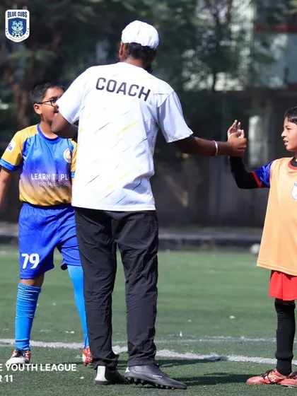 A coach gives a high-five to a young player during a U11 Thane Youth League match, a moment of encouragement.