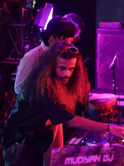 A close-up of me at work, with my long hair and focused expression under purple and red stage lights.