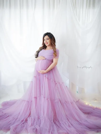 A dreamy and ethereal portrait. The mom-to-be is surrounded by soft lavender tulle, with fairy lights adding a magical glow.