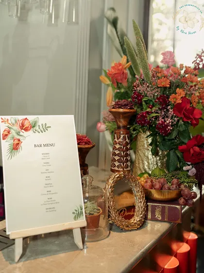 An elegant bar menu displayed on a small easel, surrounded by a lush floral arrangement. Even practical elements can be beautifully integrated into the decor.