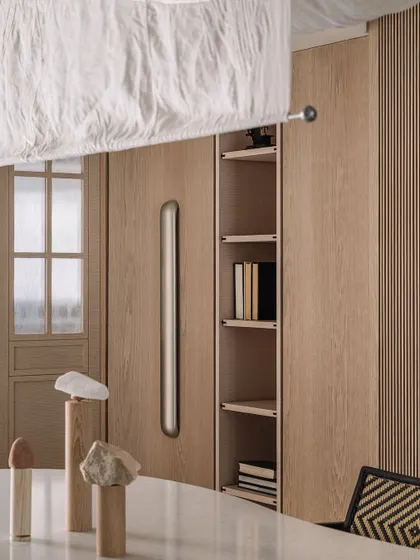 A close-up of the dining table, featuring curated stone totems and a view of the custom wood cabinetry and door handle.