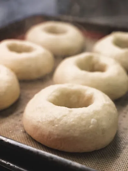 Steaming hot bagels after their bath, ready to be seasoned and baked.