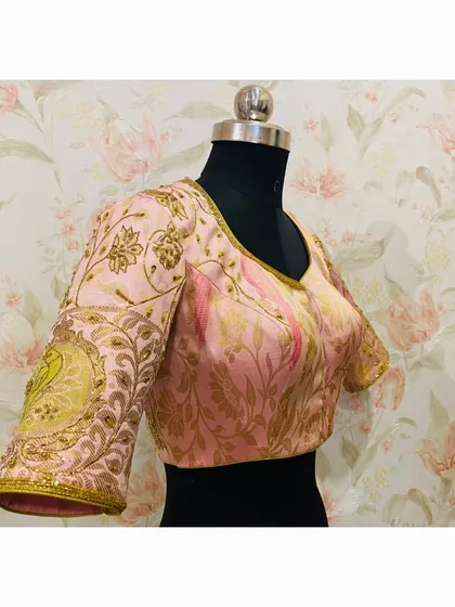 A side view of the pink blouse, highlighting the detailed peacock motif embroidered on the sleeve using zardosi and threadwork.