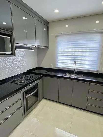 A view of the compact yet efficient L-shaped section of the Vasant Kunj kitchen. The design incorporates a built-in oven, hob, and microwave, all within easy reach of the main work area.