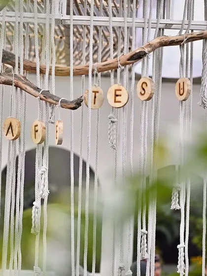 Another perspective of the hanging wooden disc sign for Cafe Tesu, showing how it integrates with the macrame and natural branch elements.