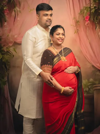 A classic and happy portrait of an expecting couple, radiating joy in their traditional red and white attire.