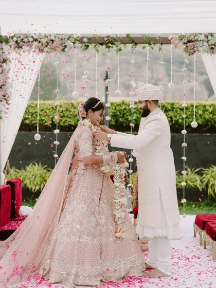 The groom places the garland on his bride during the Varmala ceremony, a key moment in their beautiful outdoor wedding.