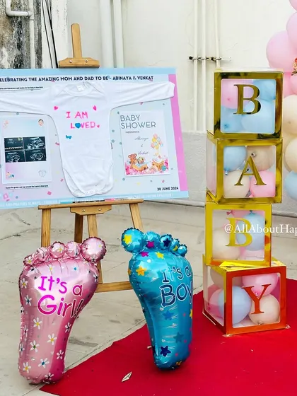 A close-up of the details from a baby shower. The setup includes a custom board with the baby's sonogram, 'It's a Boy/Girl' balloons, and 'BABY' blocks for a sweet gender reveal theme.