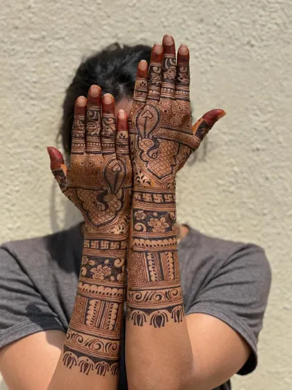 A full-arm bridal design featuring peacocks, swastikas, and floral bands.