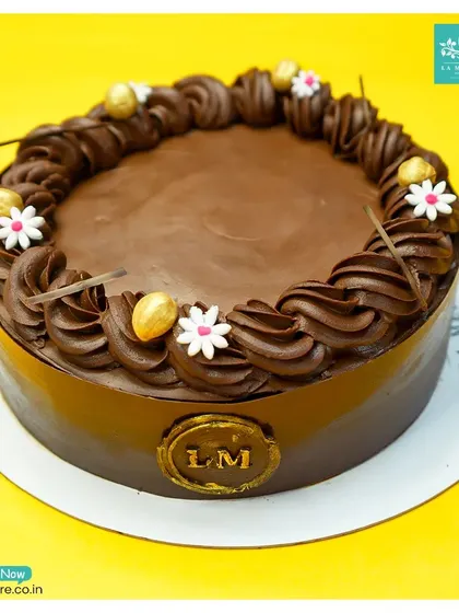 Our Chocolate Hazelnut Praline cake is pure decadence. A smooth chocolate finish is complemented by a piped border, delicate sugar flowers, and crunchy hazelnut accents.
