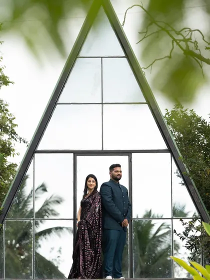 The couple posing against a modern glass structure. Their looks are coordinated to create a stylish and cohesive pre-wedding album.