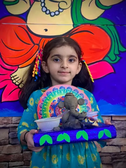 Another happy student with her finished Ganesha idol. Each child adds their own unique touch, from the decorations on the base to the colors they choose, making every creation special.