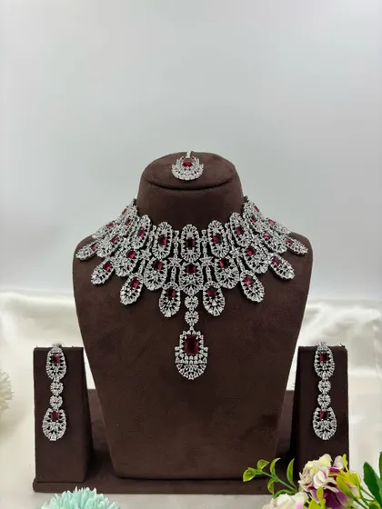 A full-coverage AD bridal set with a matching maang tikka. This silver-plated design is available in a wide range of colors like green, blue, pink, and white, making it a versatile choice for weddings.
