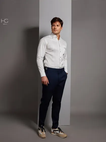 A full-length view of the sophisticated white shirt, paired with navy trousers and sneakers for a look that is both classic and contemporary.