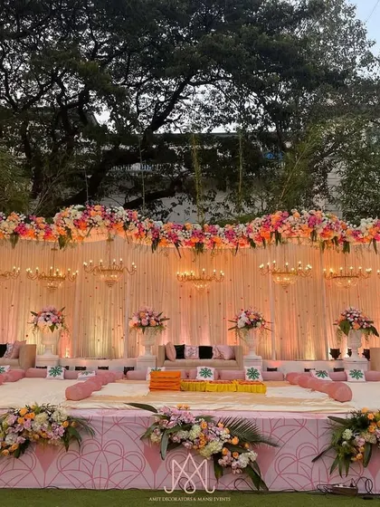 The main stage for the Mamera ceremony, featuring a backdrop of soft drapes, hanging chandeliers, and a crest of pink and peach flowers.