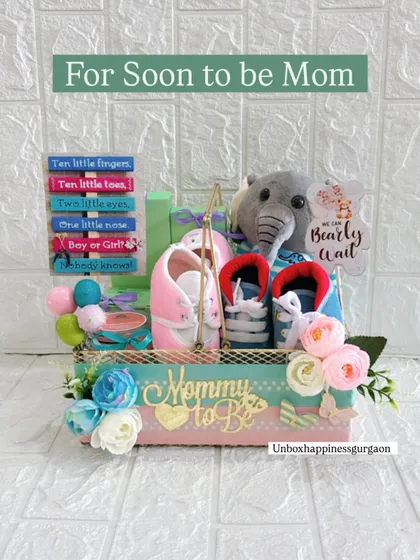 This "For Soon to be Mom" hamper is a popular choice for baby showers. It combines practical gifts like booties with sentimental items like the decorative sign and a soft plush toy.