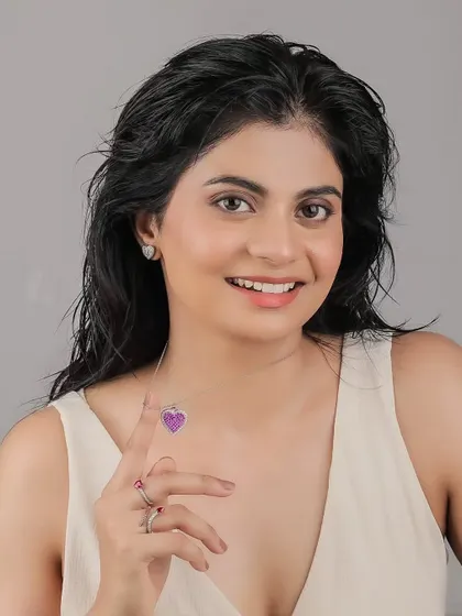 A happy and engaging portrait of a model showcasing a heart-themed jewelry set. Her direct gaze and smile make the product feel more accessible and desirable.