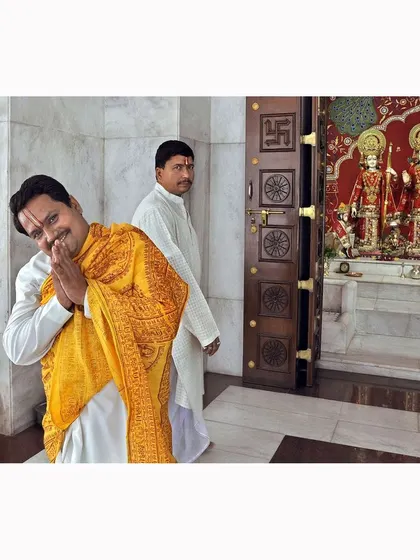 A priest offers a welcoming 'namaste' inside the temple. This candid moment captures the warmth and hospitality central to the community's faith and practice.