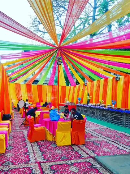 A vibrant outdoor setup for a 'Welcome Baby' get-together. The rainbow-colored ceiling drapes create a cheerful canopy over the entire seating area.