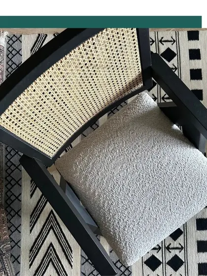 A top-down view of our Chandigarh Chair, highlighting the beautiful contrast between the black-finished oak frame, the natural cane weave, and the textured seat cushion, all set against a patterned rug.