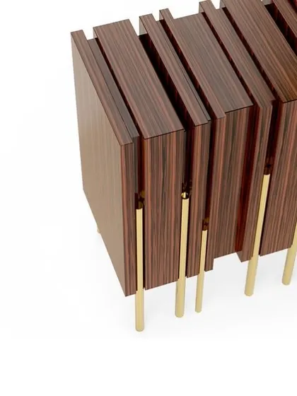 A detail shot of the "Glory" sideboard, highlighting the contrast between the dark wood veneer and the slender, polished brass legs.