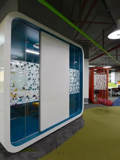 A meeting pod with rounded corners and a clean white finish, creating a futuristic look. These pods are placed throughout the open office to provide on-demand private space.