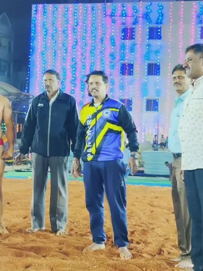 Addressing the crowd and wrestlers at a night-time Dangal event. These competitions are important community gatherings.