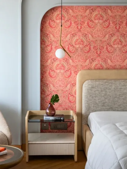 The second floor of the Slender House is designed for the two daughters. This bedroom features a vibrant, patterned wallpaper in an arched niche, reflecting a unique and artistic personality.