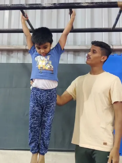 This image is a duplicate of 37, showing a coach spotting a young gymnast on the monkey bars. This is a great way to build foundational upper-body strength.